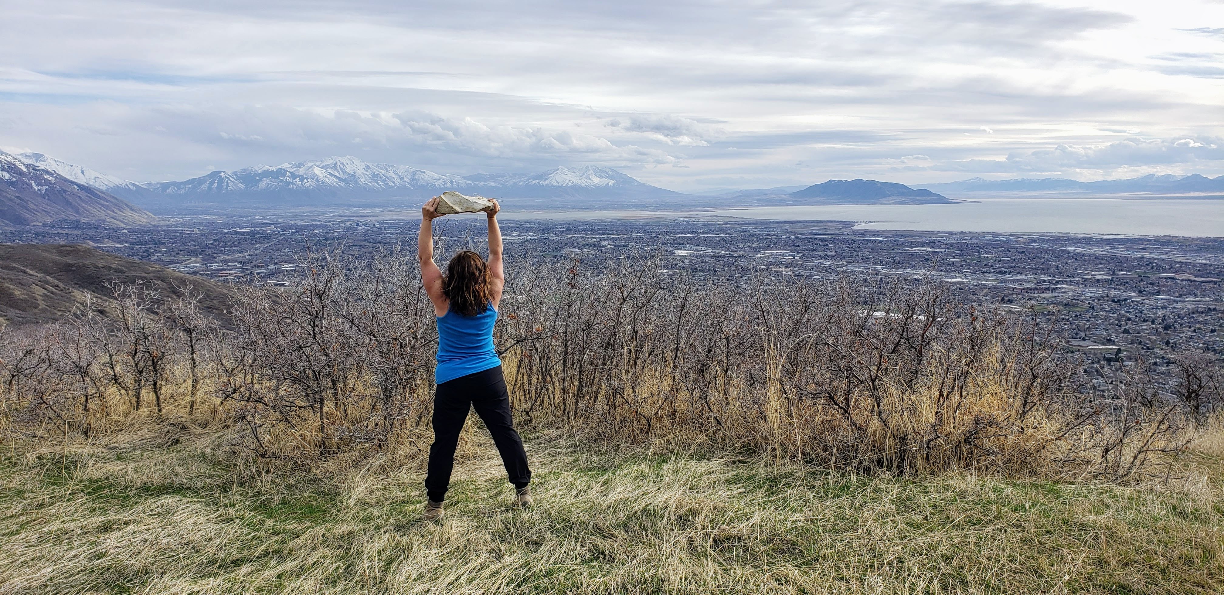 Person standing holding a heavy rock above their head representing overcoming challenges