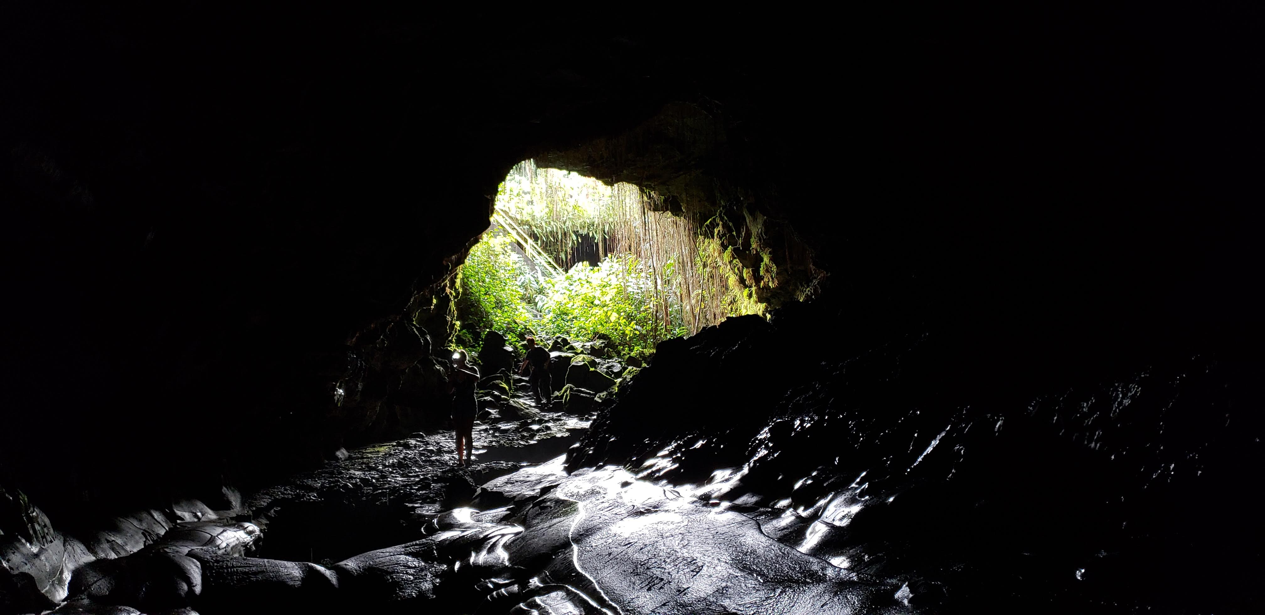 Person standing inside a dark cave with a light representing hope